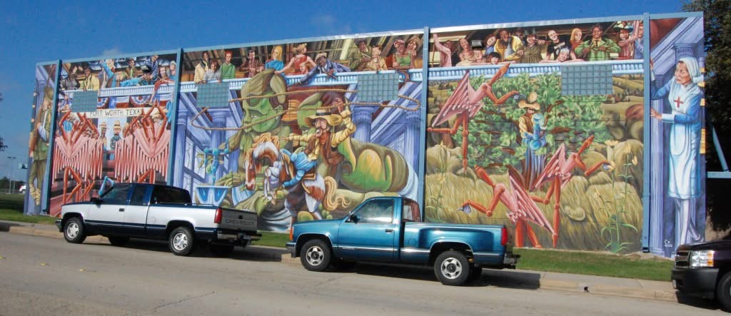 Colorful mural covering the Southwest Community Center’s exterior wall, with two pickup trucks parked in front.